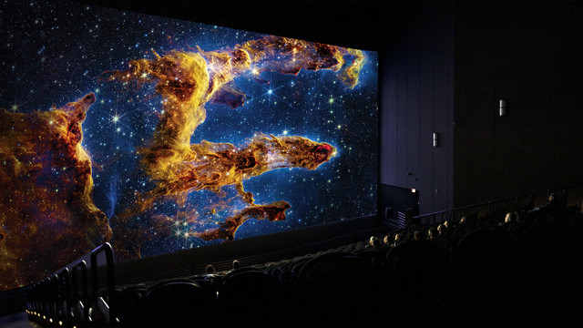 Partially full IMAX theatre with nebulae and space objects displaying on the IMAX screen