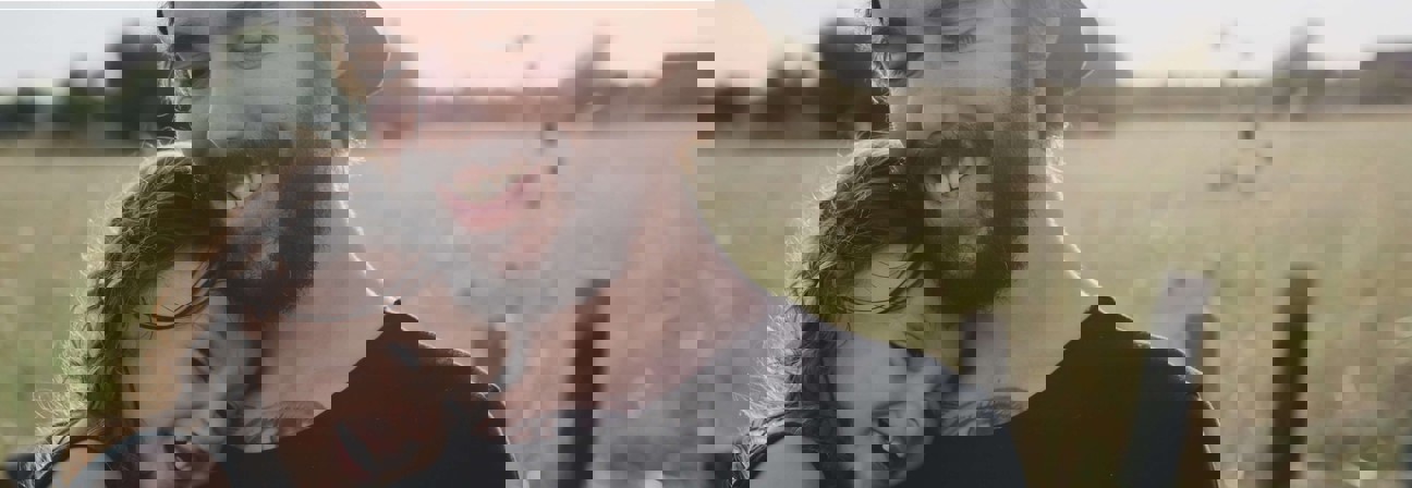 A man and woman taking a selfie in a field.