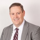 A man in a suit smiling.