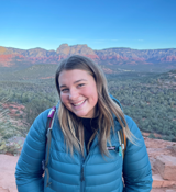 A woman smiling with a canyon in the background.