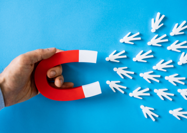 A hand holding a red handled scissors.