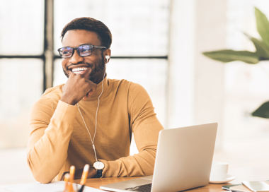 A man sitting at a desk with a laptop and headphones.