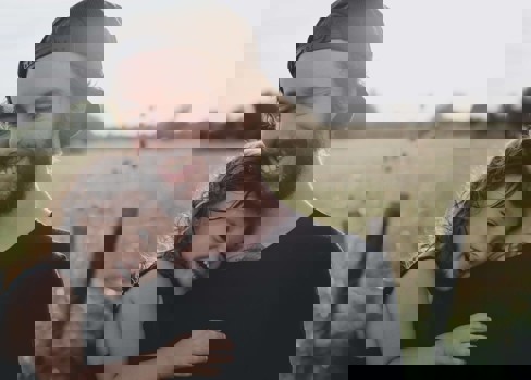 A man and woman taking a selfie in a field.