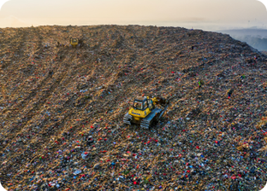 A truck driving through a large pile of trash.