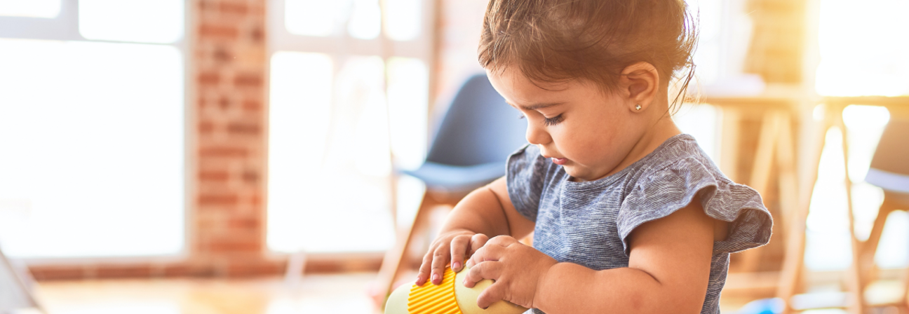 A baby playing with a yellow toy.