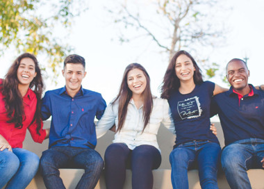 A group of young people sitting together smiling.